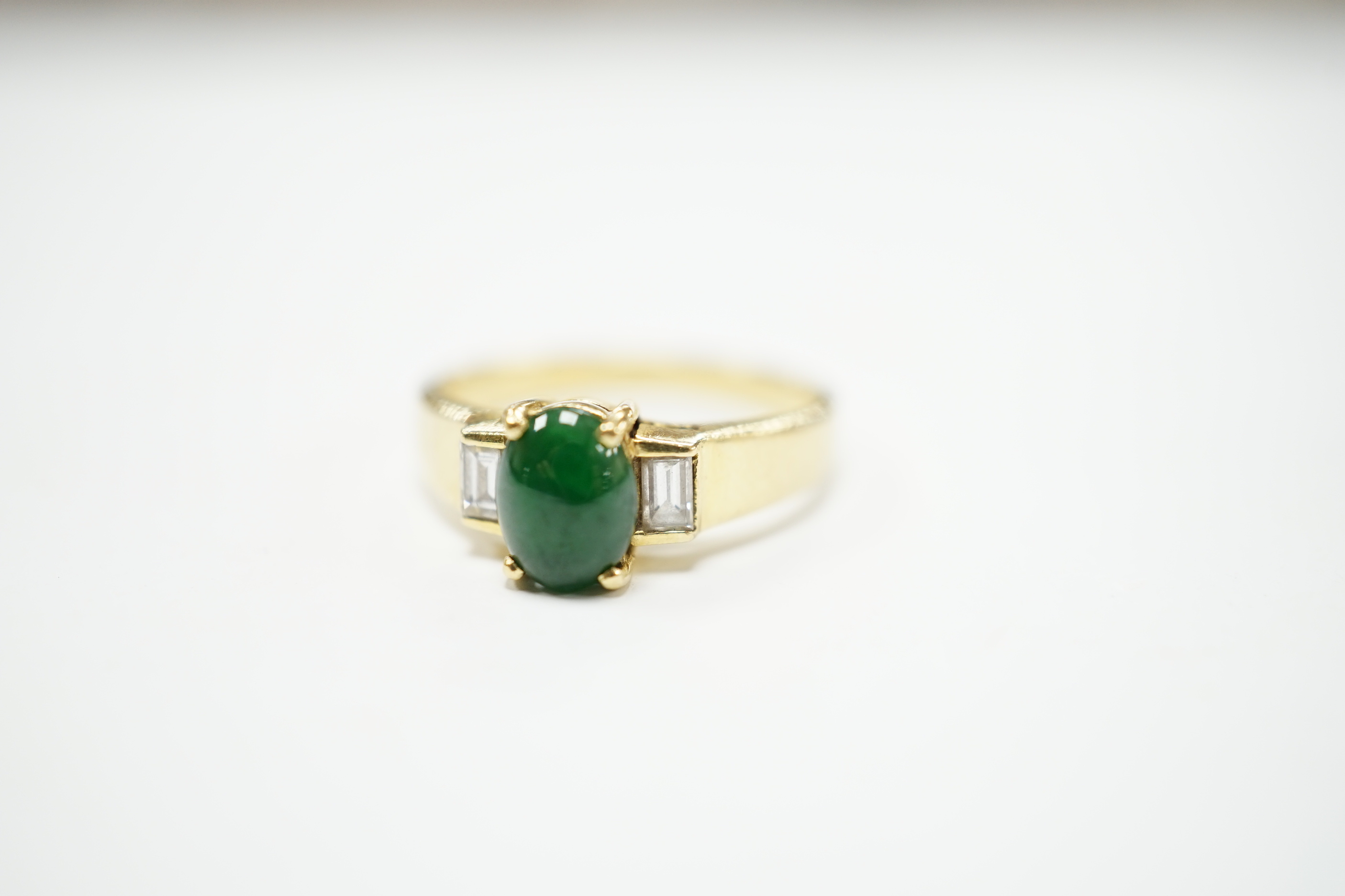A 750 yellow metal, single stone cabochon jade and two stone baguette cut diamond set ring, size M, gross weight 4.8 grams.